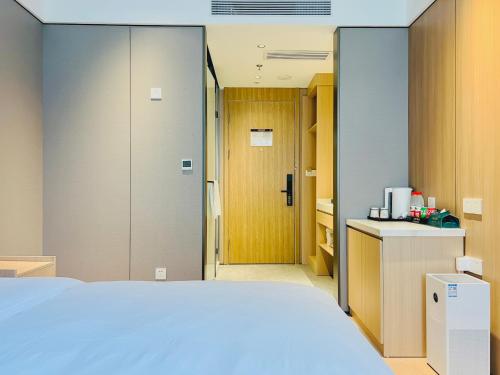 a bedroom with a white bed and a kitchen at Dayin Garden Hotel -People's Square & Nanjing Road-Large Social Area -Bar -Café -Gym -Free Laundry Luggage Storage -24H Front Desk-English Service in Shanghai
