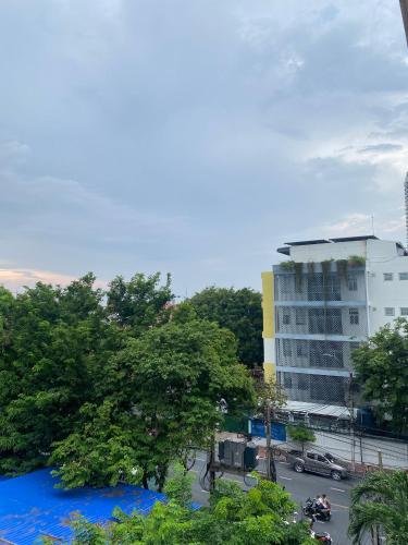 a tall white building with trees and a street at New Siam II in Bangkok