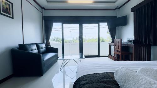 a bedroom with a bed and a couch and a chair at EZ House in Sukhothai