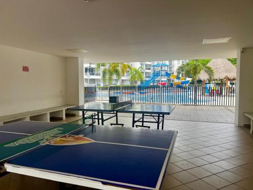 Una sala con tres mesas de ping pong y un parque infantil. en Escapate al sol en La Morada Peñazul apartamento BBQ, en Ricaurte