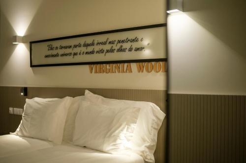 a sign above a bed with white pillows at Azores Book Hotel in Angra do Heroísmo