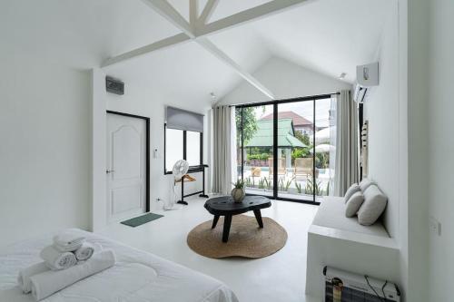 a white bedroom with a bed and a table at Stunning Pool Villa - In Old Town Chiang Mai Daily Housekeeping in Chiang Mai