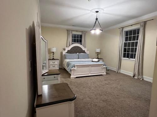a bedroom with a white bed and two windows at Beautiful River front home with private pool in Phillipsburg