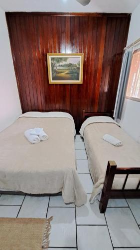 two twin beds in a room with wooden walls at Pousada Luar de Penedo in Penedo