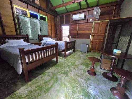 a bedroom with two beds and a tv in it at โอบสุขโฮมสเตย์ Oob-Suk in Ban Mae Cho