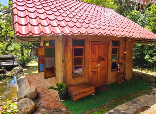 a small wooden house with a red roof at โอบสุขโฮมสเตย์ Oob-Suk in Ban Mae Cho