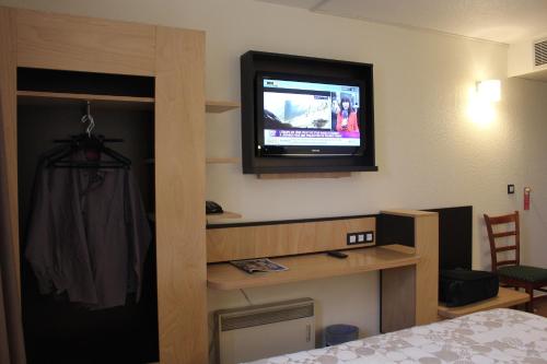 a hotel room with a tv on the wall at Euro Hôtel Airport Orly Rungis in Fresnes