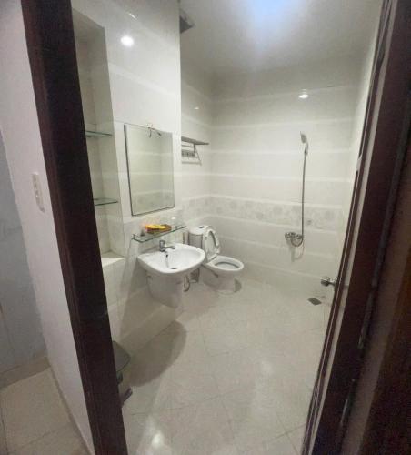 a white bathroom with a sink and a toilet at Quang Huy Hotel in Ho Chi Minh City