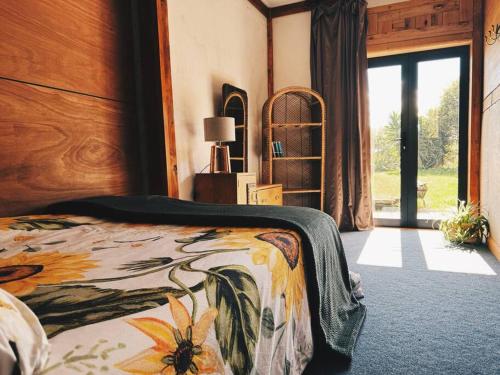 a bedroom with a bed with a bedspread with flowers on it at Wake up and Thrive in Raglan