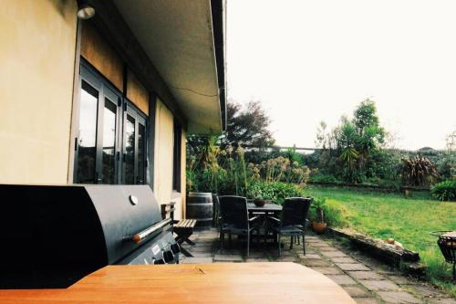 a patio with a table and chairs and a field at Wake up and Thrive in Raglan