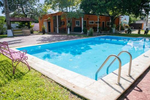 a swimming pool with a bench in front of a house at A unos pasos del paraíso in Hunucmá