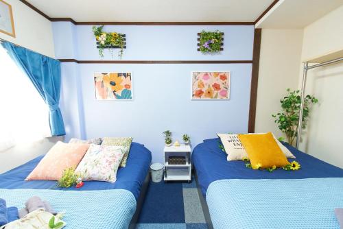 two beds in a room with blue walls at Belmont 101 3min to Station Easy Access Ueno Asakusa Skytree Sleeps 5 in Tokyo