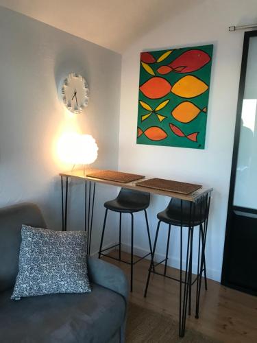 - un salon avec une table, des tabourets et une horloge dans l'établissement Magnifique studio Cassis vue mer, à Cassis