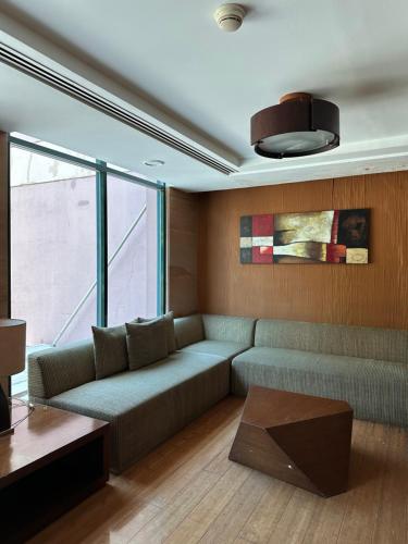 a living room with a couch and a large window at Studio One Condominium, Alabang - Bluu - Fiber Wi-Fi, Netflix-ready in Manila