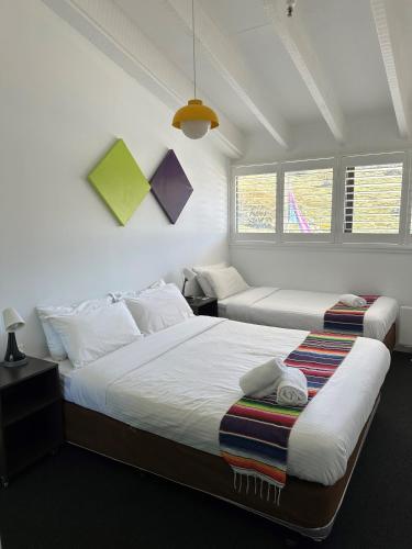two beds in a bedroom with two windows at Stillwell Hotel in Charlotte Pass
