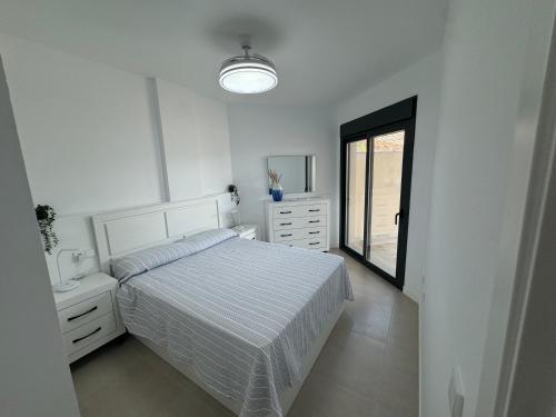 a white bedroom with a bed and a window at Niza Playa in Almayate Alto