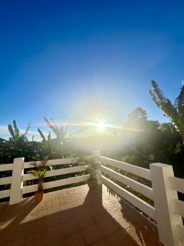 a white fence with the sun in the sky at Kindred Farm B&B Homestay in Galicias