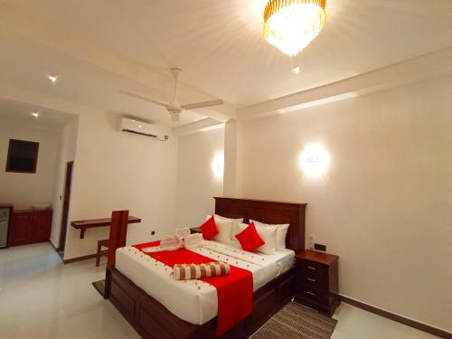 a bedroom with a large bed with red pillows at Crown Breeze in Ahangama