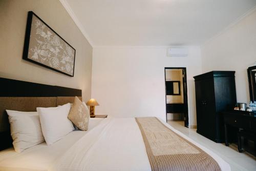 a bedroom with a large white bed with white pillows at Sarinande Hotel in Seminyak