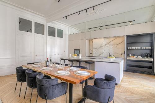 Un comedor con mesa y sillas y una cocina. en Appartement d'exception Lyon 6e, en Fourvière