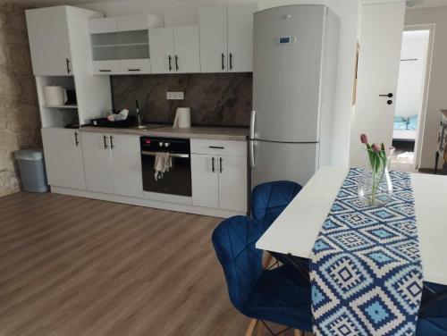 a kitchen with white cabinets and a table with a blue chair at Stone Vendégház Tisza-tó in Poroszló