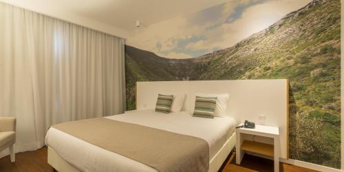 a bedroom with a bed with a painting on the wall at Steyler Fatima Hotel & Congress in Fátima