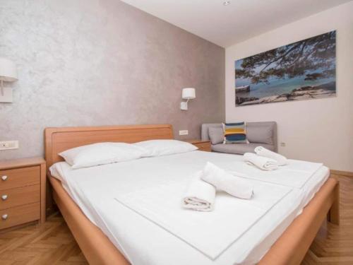 Un dormitorio con una gran cama blanca y una silla. en Apartments Antonio - One Bedroom Apartment with Balcony and Sea View - 3, en Tučepi