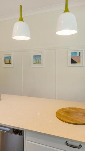 a white kitchen with a wooden cutting board on a counter at The Pines - Stylish, Brand new home in Mullumbimby