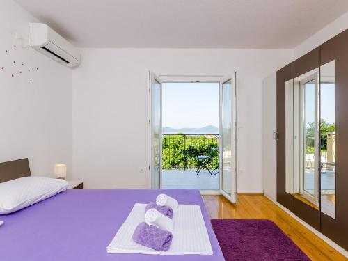 a bedroom with a purple bed and a balcony at Apartment & Rooms Ma din - One Bedroom Apartment with Balcony and Sea View in Slano