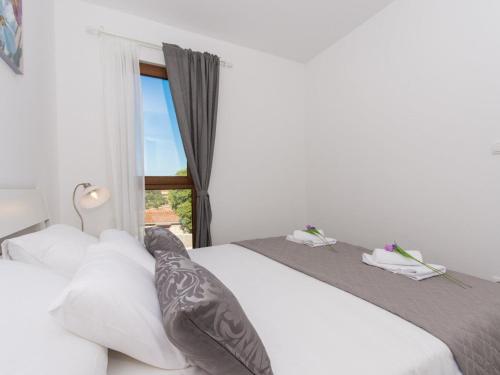 a bedroom with a bed with white sheets and a window at Villa LA-Comfort One Bedroom Apartment with Sea View Terrace 1 in Veliki Drvenik