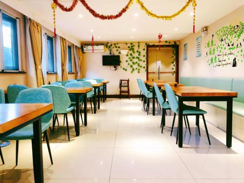 a dining room with wooden tables and green chairs at 无锡东方枫韵商务酒店惠山万达店 in Mazhen