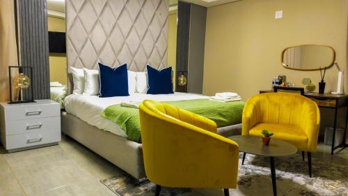 a bedroom with a bed and a chair and a table at Mercy Boutique Hotel in Thohoyandou