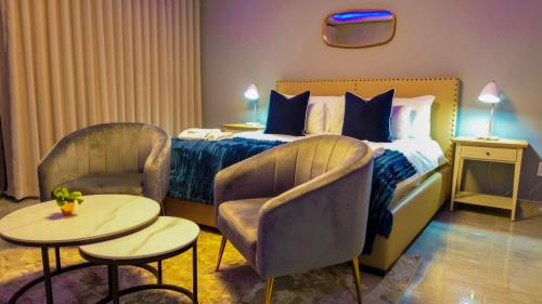 a hotel room with a bed and two chairs and tables at Mercy Boutique Hotel in Thohoyandou