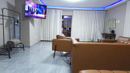 a living room with couches and a flat screen tv at Mercy Boutique Hotel in Thohoyandou