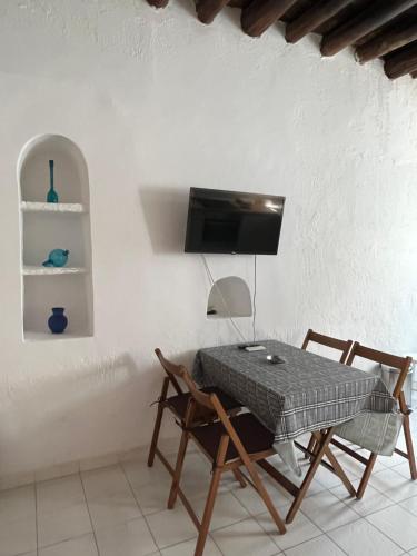 a dining room with a table and chairs and a tv at Neoclassical apartment, Central Chora Andros in Andros