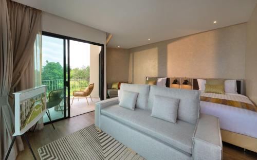 a bedroom with a couch and a bed and a balcony at Aviyana Hua Hin in Cha Am