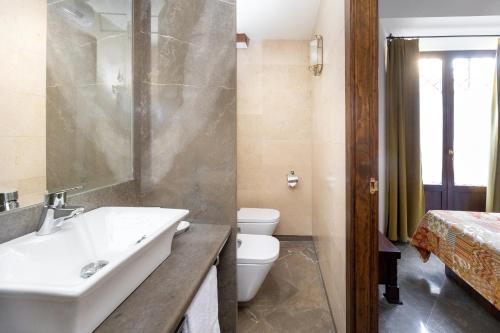 a bathroom with a sink and a toilet and a bed at Aljibe Rodrigo del Campo 1B in Granada