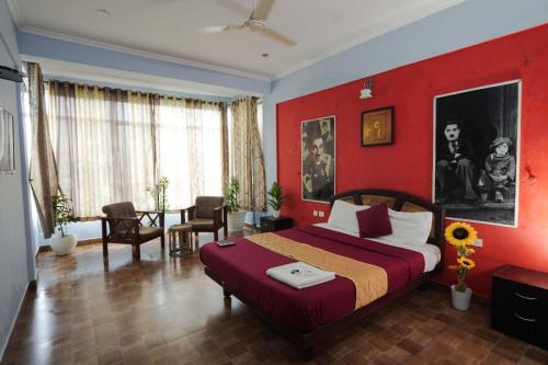 a bedroom with a red wall with a bed and a table at Vaga Hills Resort by Red Rabbit in Vagamon
