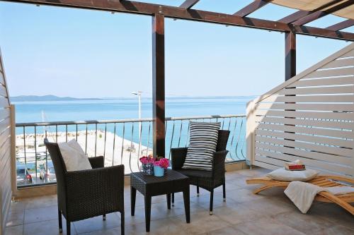 a balcony with chairs and a table with a view of the beach at Hotel Delfin in Zadar