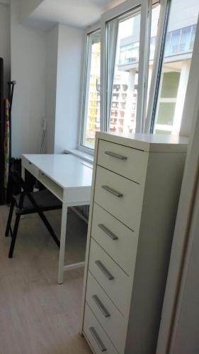 a white desk and a table in a room with a window at cosy flat in the city center in Gornyy Gigant