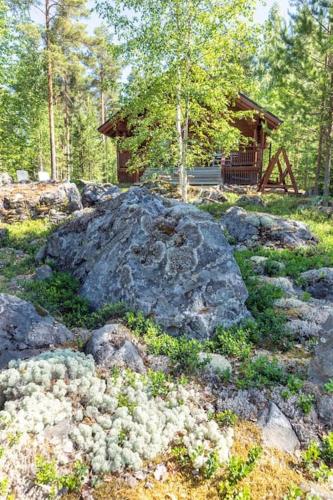 a large rock in the grass with a cabin in the background at Poukama Cottage Päijätsalo in Sysmä