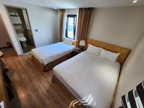 a hotel room with two beds and a mirror at Hotel Haema in Jeju