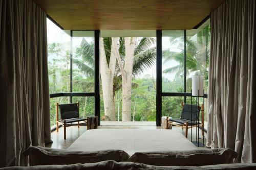 a bedroom with a large bed and a large window at Rumah Subak Tampaksiring in Tampaksiring