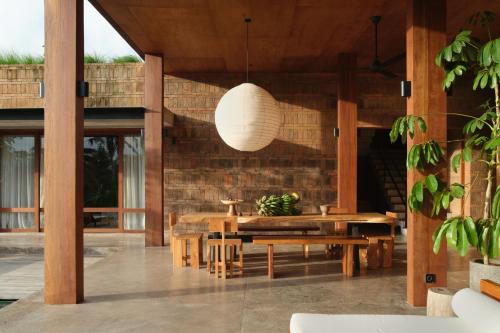 a patio with wooden tables and a pendant light at Rumah Subak Tampaksiring in Tampaksiring