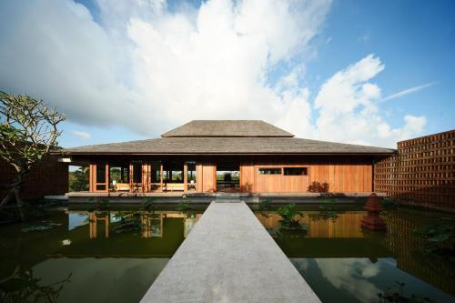 a house with a reflection in the water at Rumah Subak Tampaksiring in Tampaksiring
