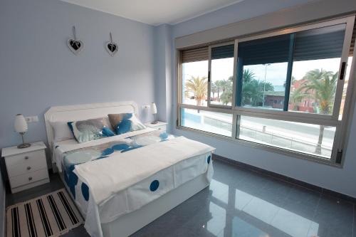 ein weißes Schlafzimmer mit einem Bett und einem großen Fenster in der Unterkunft Gran Lugar -Mar Azul in La Manga del Mar Menor