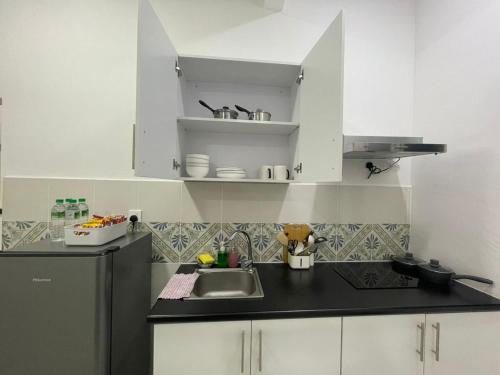 a kitchen with white cabinets and a black counter top at The Anderson Ipoh in Ipoh