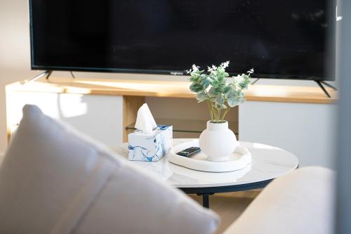 a white vase with flowers on a table with a tv at Waterloo 1Br town close to Train Shopping in Sydney