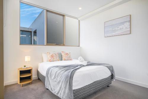 a white bedroom with a bed and a window at Waterloo 1Br town close to Train Shopping in Sydney