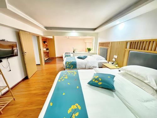 a hotel room with two beds and a television at 舒山居人文客栈 in Hanqiyu
